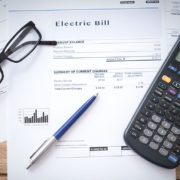 calculator, glasses and pen on top of electrical bill while potential plug load energy savings are being calculated