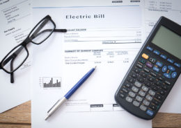 calculator, glasses and pen on top of electrical bill while potential plug load energy savings are being calculated